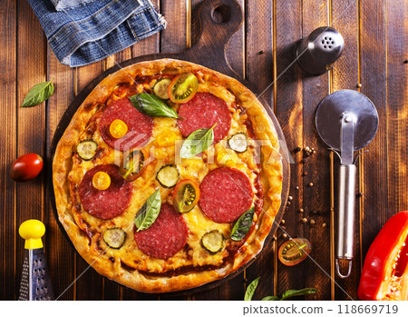 Tasty pepperoni pizza with basil on wooden table Tasty pepperoni pizza with basil on wooden table 118669719