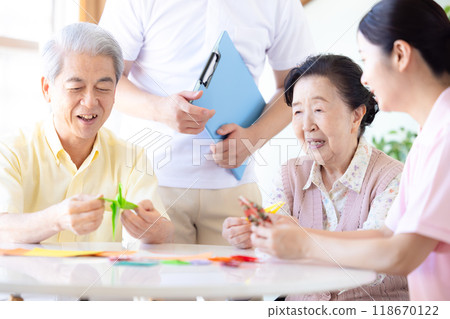 Care image: Seniors and caregivers folding origami Care image: Seniors and caregivers folding origami 118670122