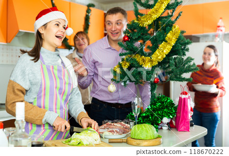 Young woman cooking salad for christmas dinner, man helping Young woman cooking salad for christmas dinner, man helping 118670222