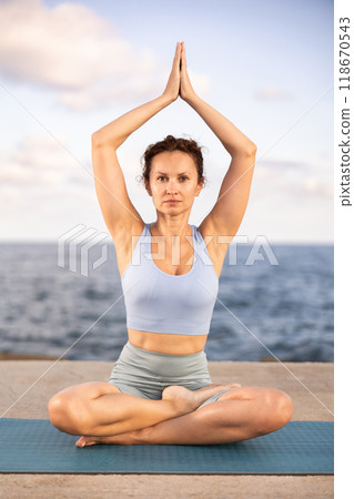 Yoga practice on embankment, female athlete fulfil carry out padmasana svastikasana, Siddhasana 118670543