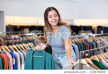 Young woman choosing warm cardigan in store Young woman choosing warm cardigan in store 118670609