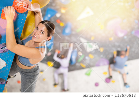 Young woman practicing rock climbing on climbing wall Young woman practicing rock climbing on climbing wall 118670618