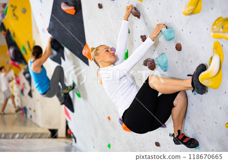Positive woman training at bouldering gym without special climbing equipment 118670665