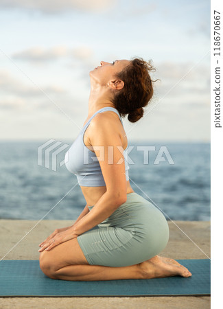 Yoga practice on embankment, female athlete fulfil carry out padmasana svastikasana, Siddhasana 118670667