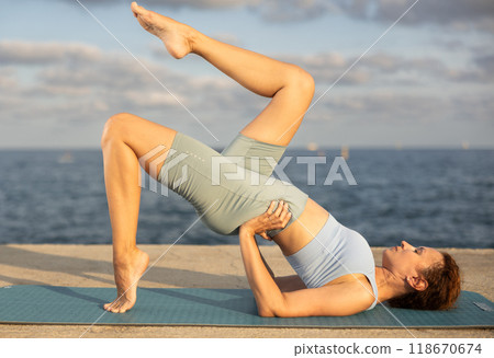 Atletic woman practitioner of yoga performing headstand, maintaining poised control and showcasing flexibility 118670674