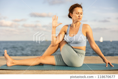 Yoga practice on embankment, female athlete fulfil carry out wakrasana 118670677