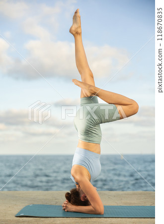 Yoga practice on embankment, female athlete fulfil carry out shirshasana Yoga practice on embankment, female athlete fulfil carry out shirshasana 118670835