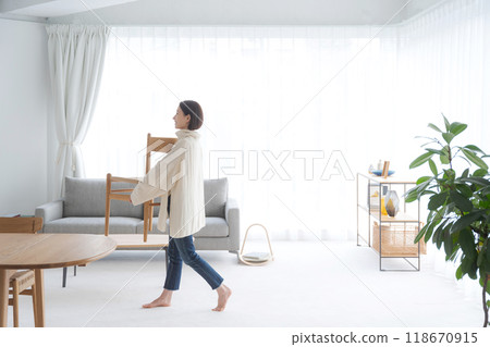 Woman moving a chair in the living room 118670915