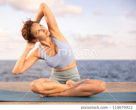 Yoga practice on embankment, female athlete fulfil carry out padmasana svastikasana, Siddhasana Yoga practice on embankment, female athlete fulfil carry out padmasana svastikasana, Siddhasana 118670922