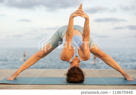 Yoga pose called pyramid performed by a woman on seashore 118670948