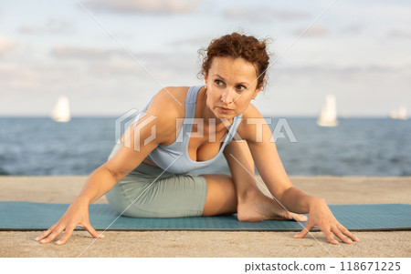 Ardha Matsyendrasana yoga pose - woman doing yoga On beach 118671225