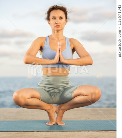 Yoga practice on embankment, female athlete fulfil carry out Prapadasana Yoga practice on embankment, female athlete fulfil carry out Prapadasana 118671342
