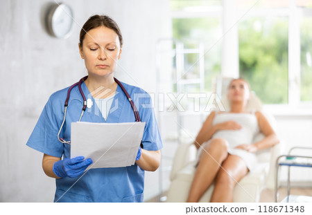 Adult woman doctor posing with contract in medical room 118671348