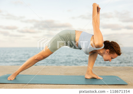 Yoga practice on embankment, female athlete fulfil carry out elongated side angle 118671354