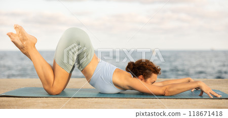 Woman in yoga pose on seashore - dog pose Woman in yoga pose on seashore - dog pose 118671418
