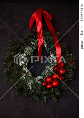 Wreath with red ribbon and red balls on a dark background Wreath with red ribbon and red balls on a dark background 118671419