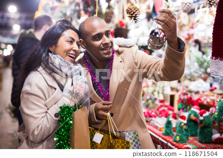 Cheerful man and woman buying christmas balls together at christmas fair Cheerful man and woman buying christmas balls together at christmas fair 118671504