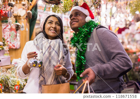 Emotional happy couple buying christmas balls at christmas fair Emotional happy couple buying christmas balls at christmas fair 118671558