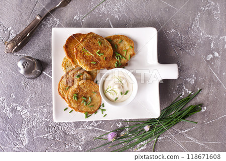 Fried potato pancakes with white sauce on plate Fried potato pancakes with white sauce on plate 118671608