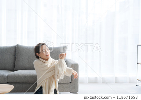 Young woman stretching while sitting on the floor in the living room 118671658