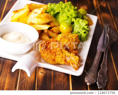 Delicious fried chicken wings accompanied by golden potato wedges served with creamy sauce Delicious fried chicken wings accompanied by golden potato wedges served with creamy sauce 118671756