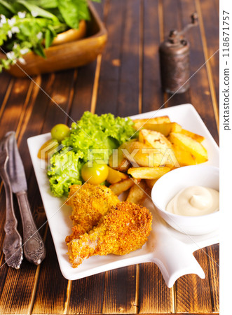 Delicious fried chicken wings accompanied by golden potato wedges served with creamy sauce 118671757