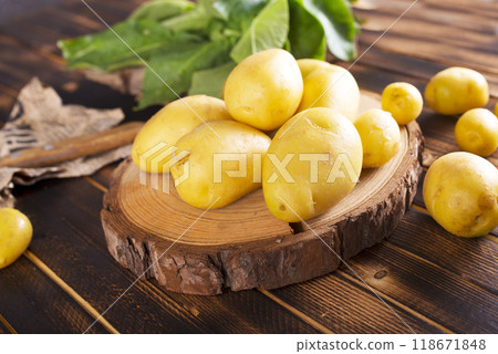 Raw potato on wooden board 118671848