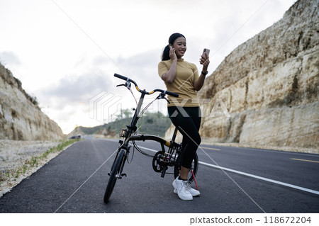female biker using phone and earphone when biking 118672204