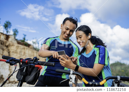 female and male biker using phone riding bicycle 118672258