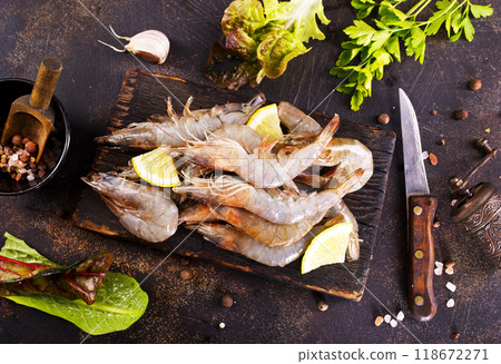 Raw tiger white shrimp prawn on board with herbs. Dark background. Top view. Raw tiger white shrimp prawn on board with herbs. Dark background. Top view. 118672271