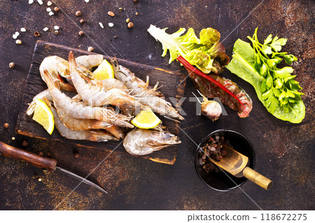 Raw tiger white shrimp prawn on board with herbs. Dark background. Top view. Raw tiger white shrimp prawn on board with herbs. Dark background. Top view. 118672275