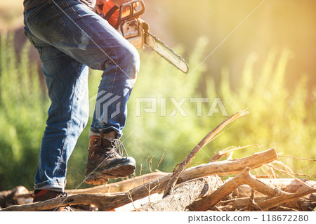 A closeup view of a person actively operating a powerful chainsaw in a serene and tranquil outdoor setting, copy space. 118672280