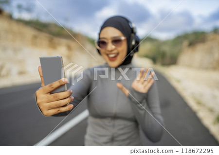 sporty hijab woman using phone with waving gesture 118672295