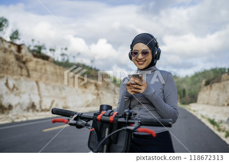hijab woman using phone when riding bike hijab woman using phone when riding bike 118672313