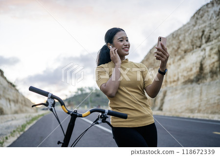 female cyclist riding bike and using phone and earphone female cyclist riding bike and using phone and earphone 118672339