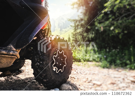 Big aggressive ATV off-road quad bike wheel against a picturesque background of nature calling for adventure. 118672362
