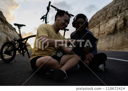 male biker presenting digital tablet female partner 118672424