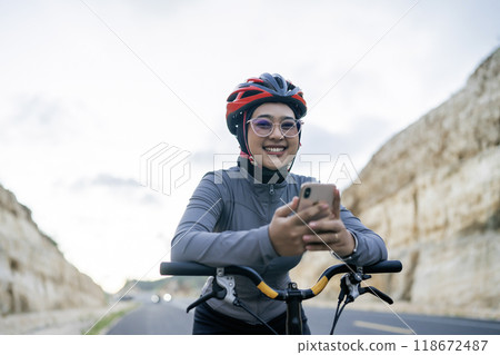 smiling female biker wearing helmet using phone 118672487