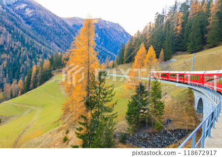 Red passenger train on Rhaetian railway in Canton Graubunden, Switzerland at autumn Red passenger train on Rhaetian railway in Canton Graubunden, Switzerland at autumn 118672917