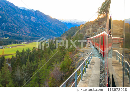Red passenger train on Rhaetian railway in Canton Graubunden, Switzerland at autumn Red passenger train on Rhaetian railway in Canton Graubunden, Switzerland at autumn 118672918