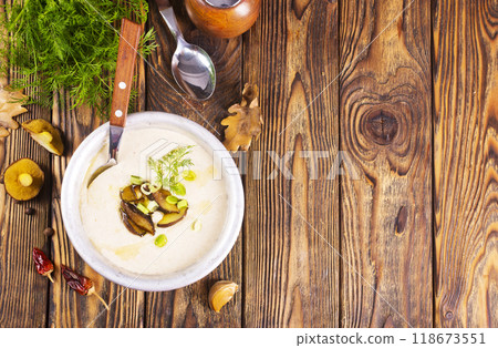 On the wooden table, there is a cream soup with fresh mushrooms as the base 118673551