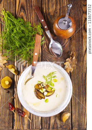 On the wooden table, there is a cream soup with fresh mushrooms as the base On the wooden table, there is a cream soup with fresh mushrooms as the base 118673552