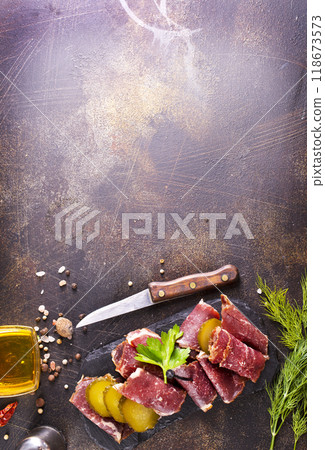 Dried Pastrami slices, beef meat with herbs on black board. Dried Pastrami slices, beef meat with herbs on black board. 118673573