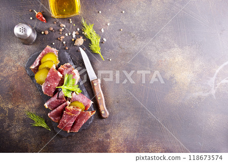 Dried Pastrami slices, beef meat with herbs on black board. 118673574