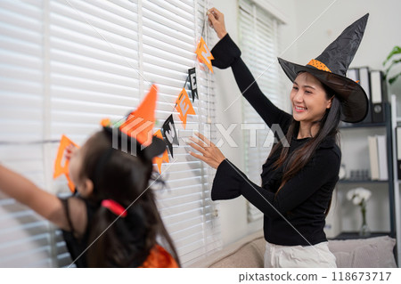 Mother and Daughter Enthusiastically Decorating Home for Halloween Celebration Mother and Daughter Enthusiastically Decorating Home for Halloween Celebration 118673717