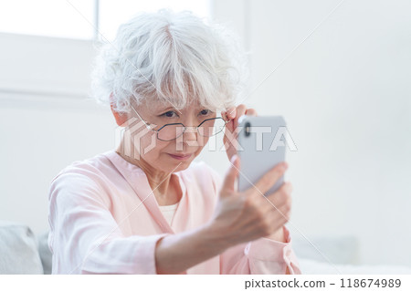Senior woman with presbyopia looking at a smartphone Senior woman with presbyopia looking at a smartphone 118674989