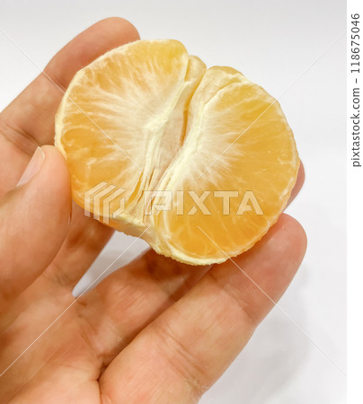 Freshly Peeled Tangerine.A close-up shot of a hand gently holding a half-peeled tangerine against a white background. 118675046