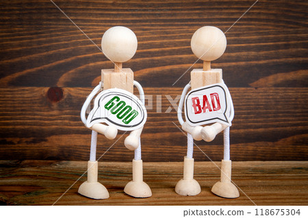 Good versus bad. Two speech bubbles and miniature people on a wooden texture background Good versus bad. Two speech bubbles and miniature people on a wooden texture background 118675304