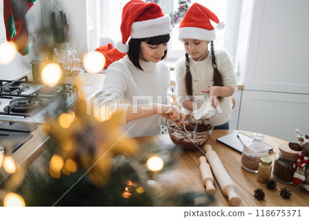 Mother and daughter baking Christmas cookies in kitchen 118675371