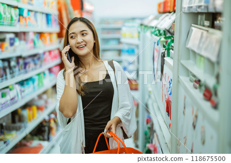 young woman makes a call while shopping carrying a cart 118675500